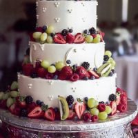 Three-tier tri-dot style cake with fresh fruit garnish.