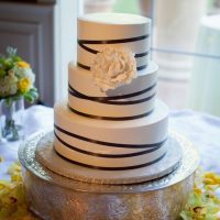 Three-tier smooth style wedding cake with ribbon detail.
