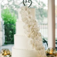 Four-tier wedding cake with fondant floral pattern.