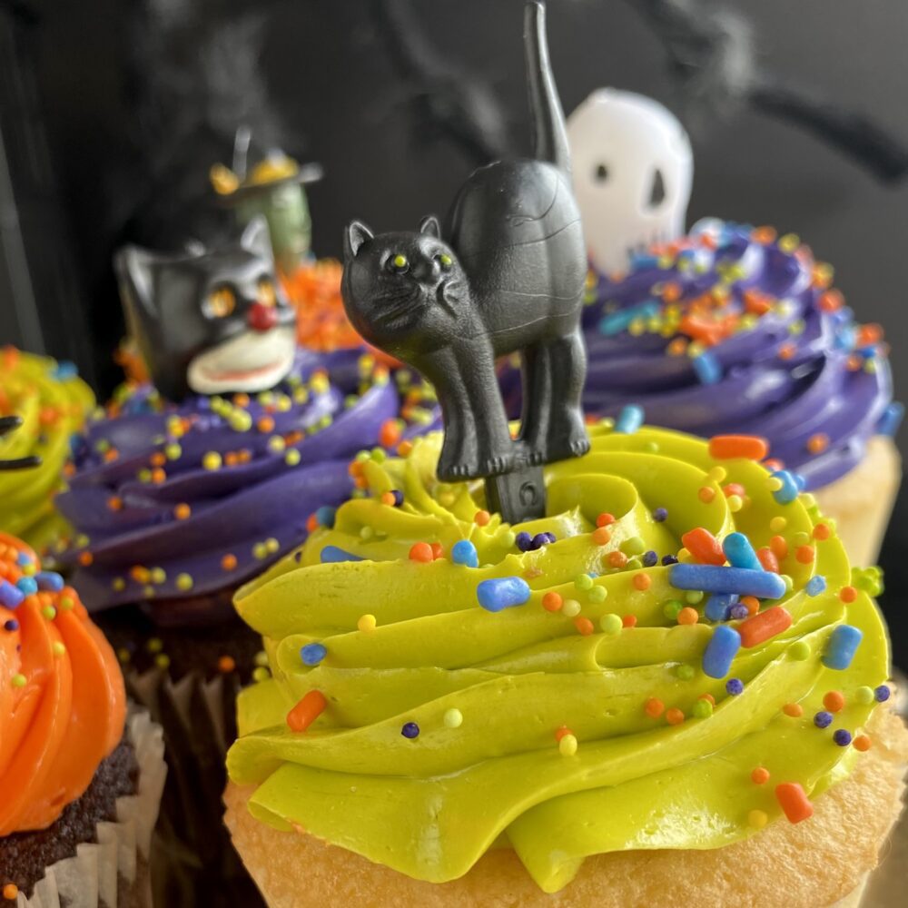 Detail of Halloween cupcakes with colored buttercream and assorted toppers.