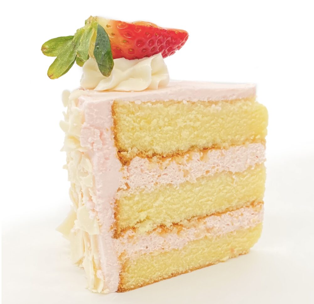 Slice of pink buttercream frosted Champagne Cake showing cake layers.