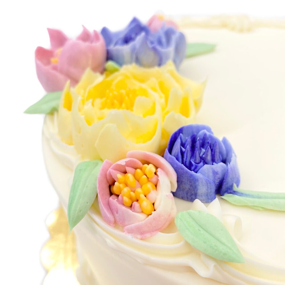 Detail of Floral Bouquet decoration on round cake frosted in white buttercream.