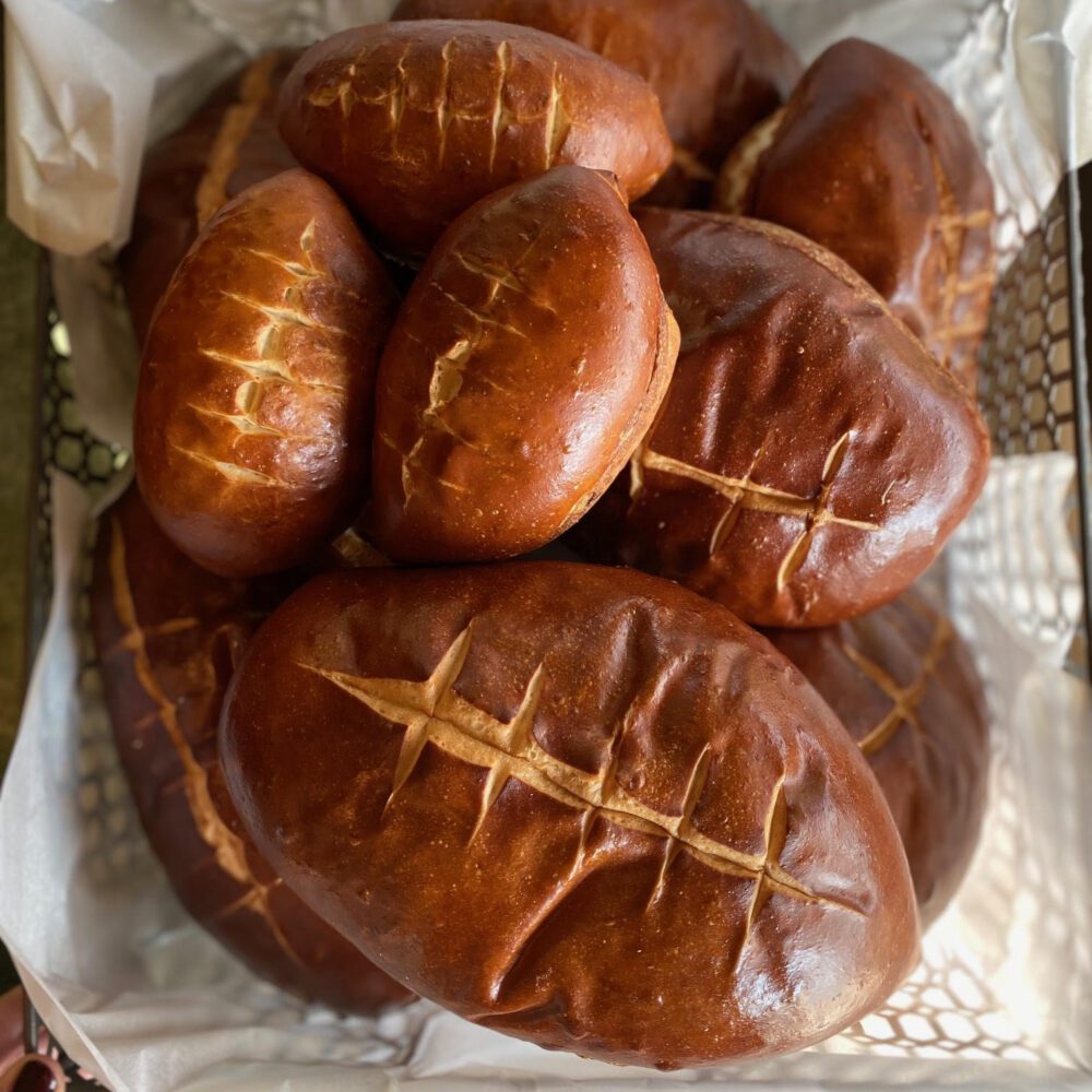 Football-shaped buns and loaf in a basket.