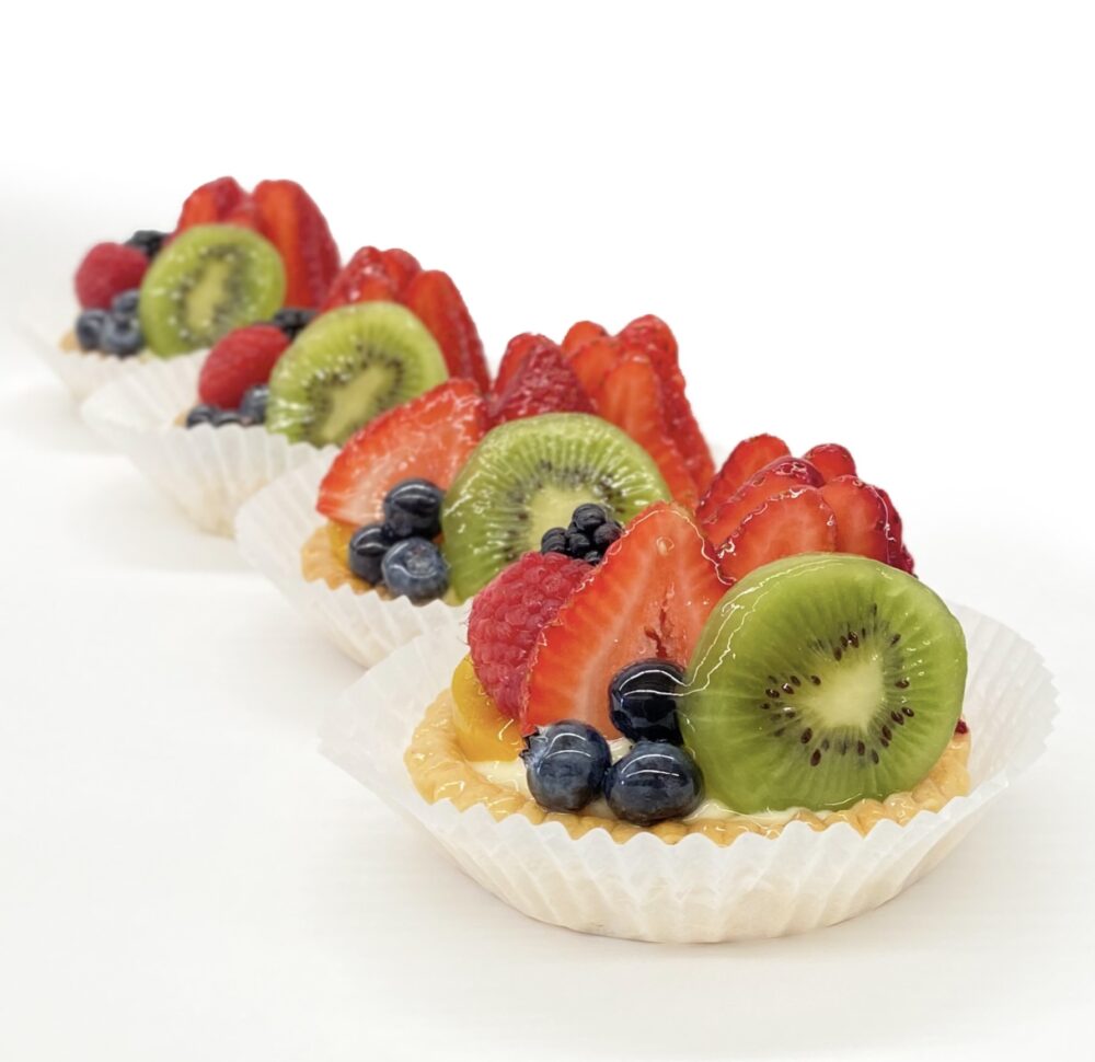 Side view of individual sized fresh fruit tarts.