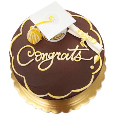 Graduation decoration on a round fudge cake with white and yellow details.