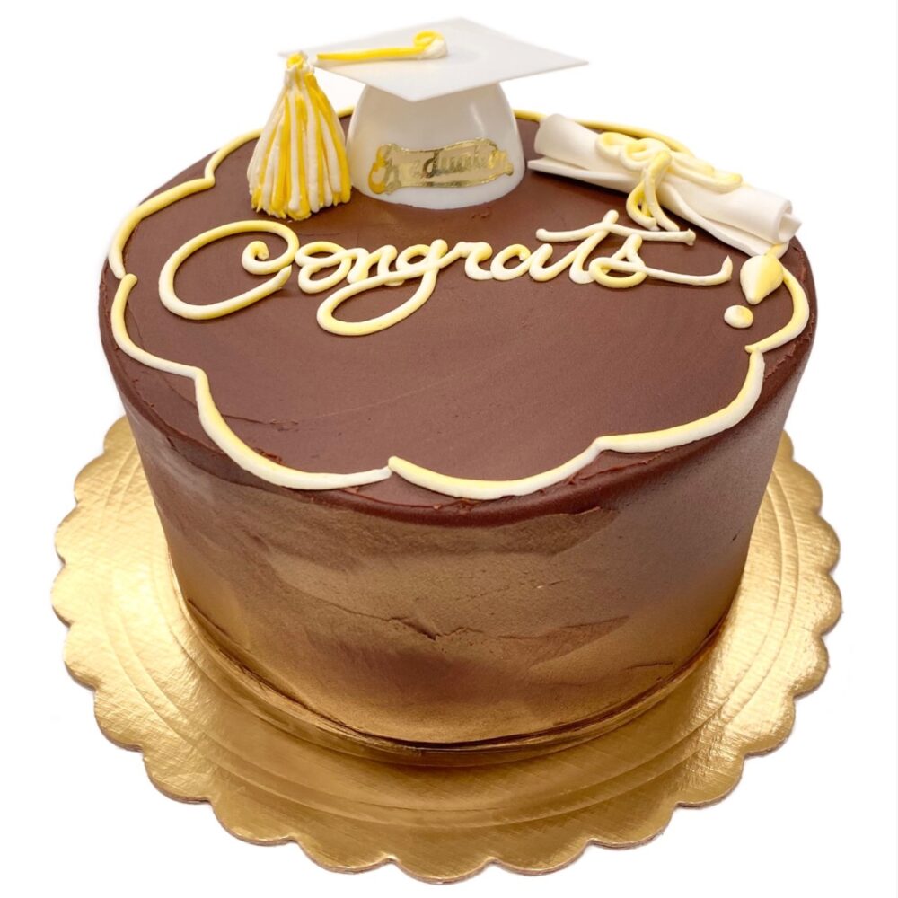 Graduation decoration on a round fudge cake with white and yellow details.