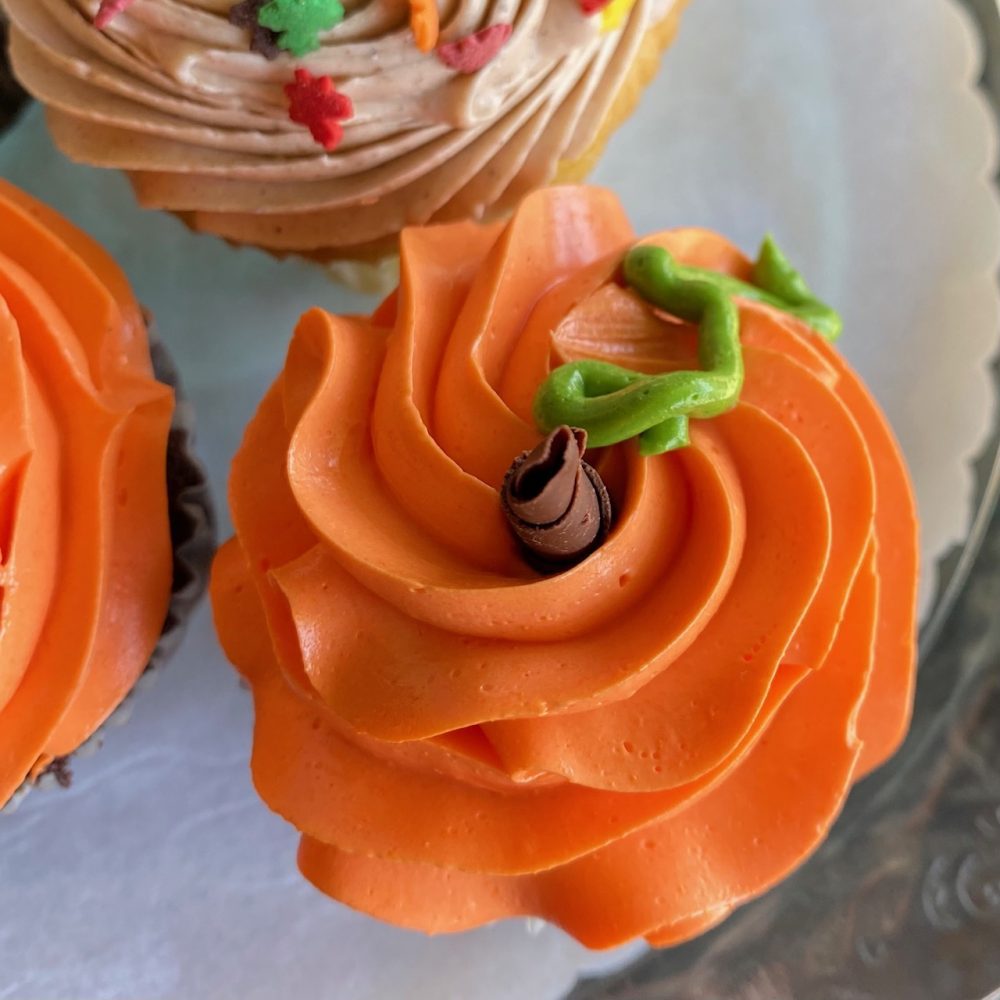 Orange frosted buttercream pumpkin-themed cupcakes.