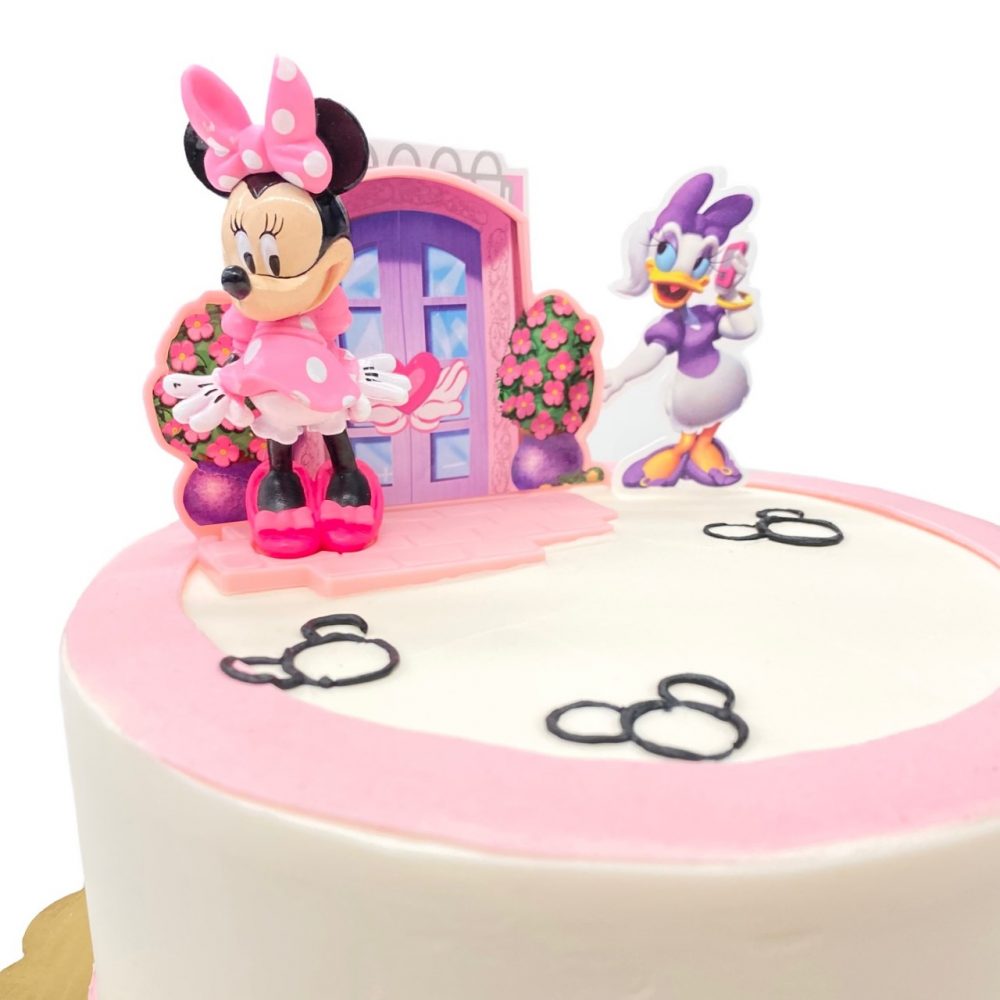 Detail of Minnie Mouse decoration on round cake frosted in white buttercream.
