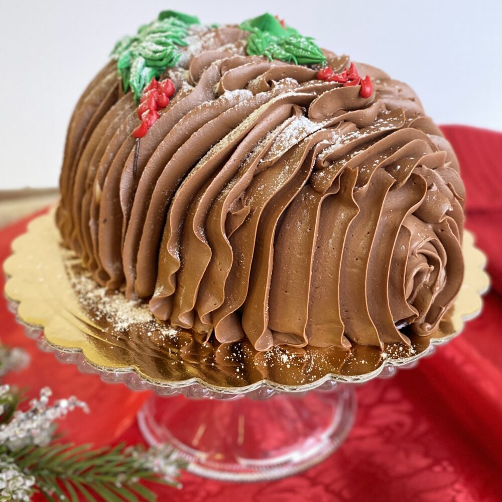 Side view of pinecone cake on a pedestal against a festive backdrop.