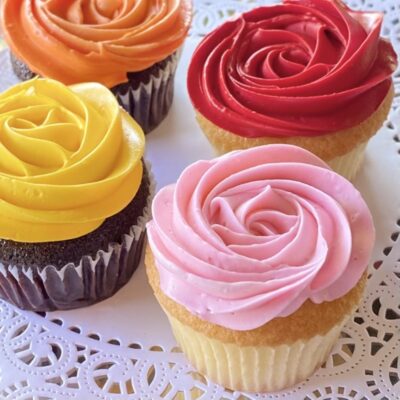 Assorted rosette style cupcakes in red, pink, yellow and orange.