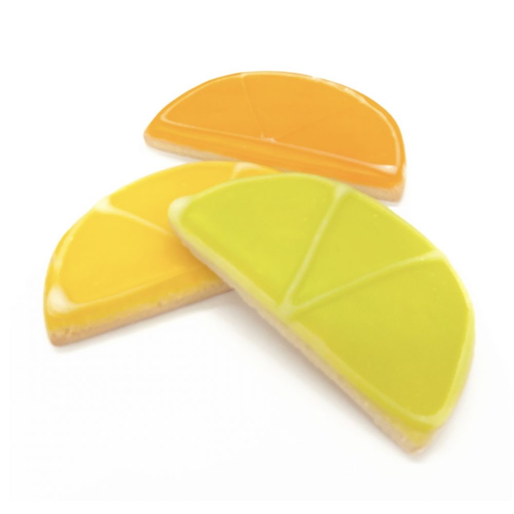 Citrus slice-shaped glazed sugar cookies in orange, green and yellow.